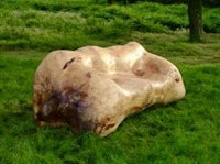 a large wooden bench in the middle of a grassy field