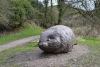 a stone statue of a rabbit on a dirt path