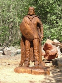 a wooden statue of a man holding a shield