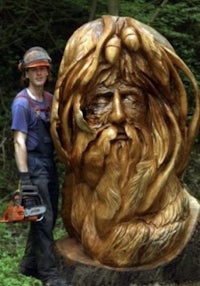 a man is carving a wooden head in the woods