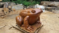 a wooden sculpture of a frog sitting on top of logs