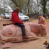 a man sits on a wooden sculpture of a deer