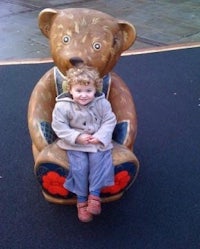 a young girl sitting on a wooden teddy bear