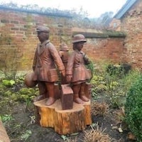 a statue of two children on a stump in a garden