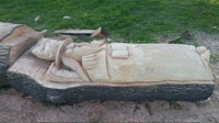 a tree trunk with a carving of a man sleeping on it