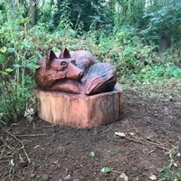 a wooden sculpture of a fox in the woods