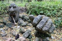 a statue of a hand in a wooded area
