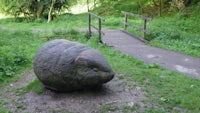 a stone sculpture of a rabbit in a grassy area