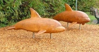 two wooden dolphin sculptures in a park