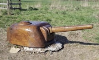 a wooden tank sitting on top of a rock in a field