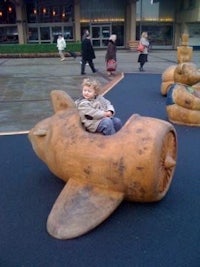 a young boy sitting in a wooden plane