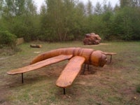 a wooden sculpture of a bug in a field