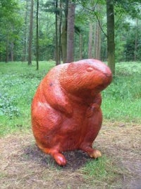 a wooden sculpture of a beaver in the woods