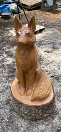 a statue of a fox sitting on a stump