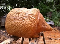 a wood carving of a hedgehog sitting on top of a log