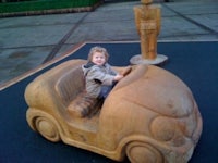 a child in a wooden car with a statue in the background