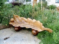 a wooden bench with a leaf on it in a garden