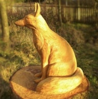a wooden sculpture of a fox sitting on a stump