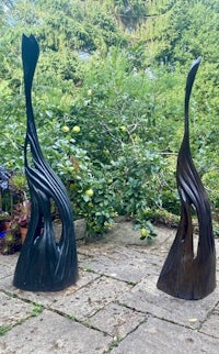 two metal sculptures on a patio in a garden