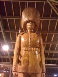 a wooden statue of a soldier standing in front of a building