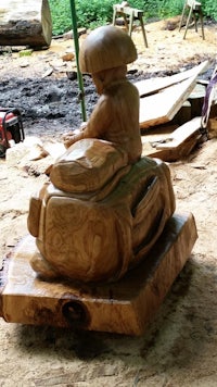 a wooden sculpture of a boy riding a bike