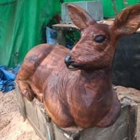 a wooden sculpture of a deer sitting on a crate