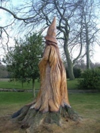 a statue of a witch on top of a tree stump
