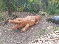a wooden crocodile statue in a garden