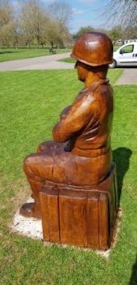 a wooden statue of a soldier sitting on a box