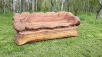 a large wooden bench in the middle of a grassy field