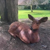 a deer statue is laying on the ground near a tree