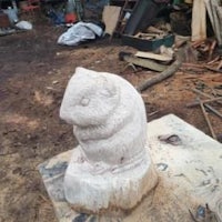 a statue of a hamster sitting on a piece of wood