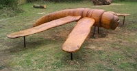 a wooden sculpture of a bug in a grassy area