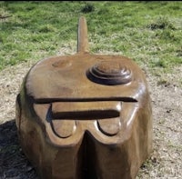 a wooden sculpture of a fish sitting in a grassy area